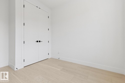 Light wood-finish flooring with white baseboards and white walls - 10531 67 Avenue Nw, Edmonton, AB - Indoor Photo Showing Other Room