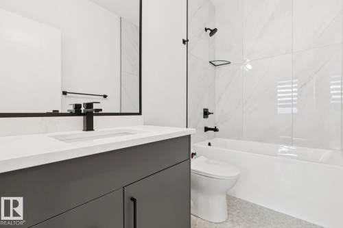 Modern bathroom featuring a dark grey vanity with a white countertop, an integrated rectangular sink, and a matte black faucet - 10531 67 Avenue Nw, Edmonton, AB - Indoor Photo Showing Bathroom