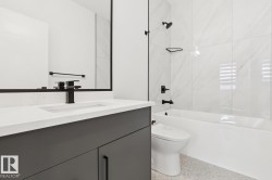 Modern bathroom featuring a dark grey vanity with a white countertop, an integrated rectangular sink, and a matte black faucet - 