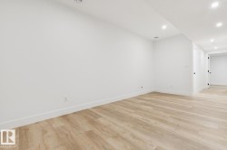 Spacious room featuring light wood-finish flooring, recessed lighting, and crisp white walls with matching baseboards - 