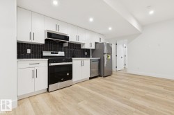 Kitchenette featuring white cabinetry, dark subway tile backsplash, stainless steel appliances, and wood-finish flooring - 