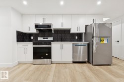 Contemporary kitchen featuring white cabinetry, stainless steel appliances, a black subway tile backsplash, light wood-finish flooring, and recessed lighting - 