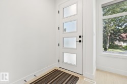 Contemporary entry door with frosted window panels and matte black hardware, accompanied by a large side window providing natural illumination - 