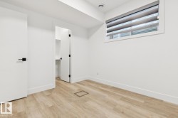 Bright room featuring wood-finish flooring, white walls, and a window with blinds - 
