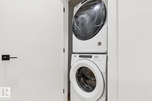 White stacked washer and dryer unit - 10531 67 Avenue Nw, Edmonton, AB - Indoor Photo Showing Laundry Room