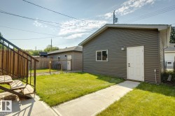 Detached structure featuring horizontal siding, a white panel door, and an exterior light fixture - 