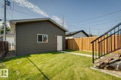 Detached garage with dark grey siding, white door, and white-framed window - 