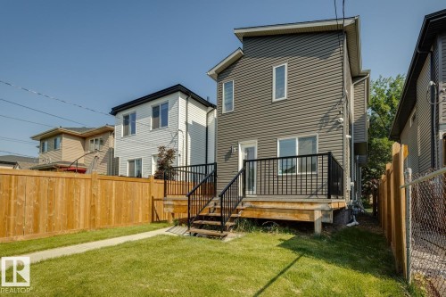 Gray horizontal siding exterior with a ground-level wood deck featuring black railings and stairs - 10531 67 Avenue Nw, Edmonton, AB - Outdoor With Deck Patio Veranda