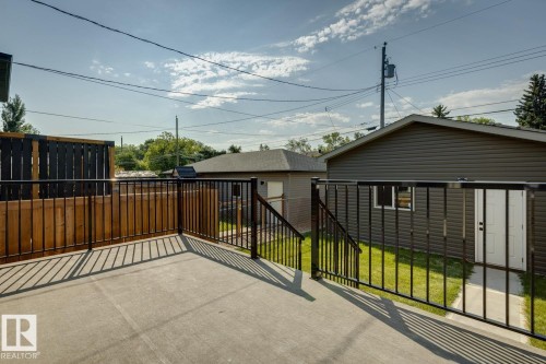 Expansive concrete patio featuring black metal railings and a wooden privacy screen - 10531 67 Avenue Nw, Edmonton, AB - Outdoor With Exterior