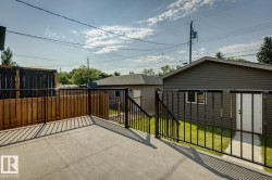 Expansive concrete patio featuring black metal railings and a wooden privacy screen - 