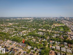 Aerial perspective showcasing a mature residential area with extensive tree canopy, featuring a prominent downtown skyline in the distance - 