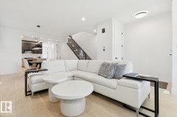Open-concept living space featuring light wood-finish flooring, white walls, and recessed lighting - 
