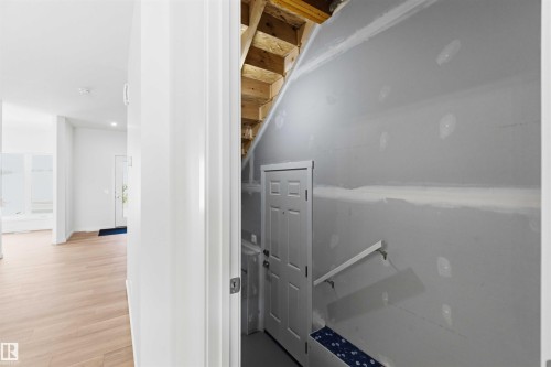 Interior hallway featuring wood-finish flooring, recessed lighting, and a white paneled door - 223 157 Avenue Ne, Edmonton, AB - Indoor Photo Showing Other Room