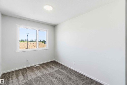 Bright interior space featuring a window with white trim, recessed ceiling light, and gray patterned carpeting - 223 157 Avenue Ne, Edmonton, AB - Indoor Photo Showing Other Room