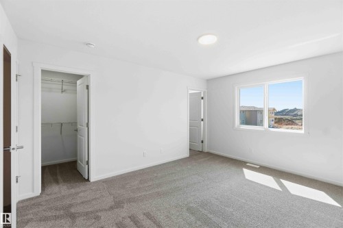 Carpeted room with white walls, a visible window, and a built-in closet with shelving and hanging rods - 223 157 Avenue Ne, Edmonton, AB - Indoor Photo Showing Other Room