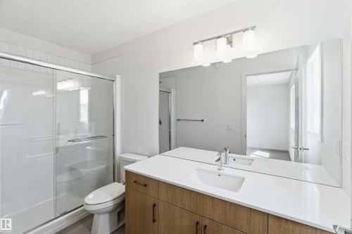 Bathroom featuring a spacious shower with sliding glass doors, white subway tile surround, and a built-in toilet - 223 157 Avenue Ne, Edmonton, AB - Indoor Photo Showing Bathroom