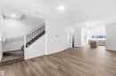 Spacious open-concept interior featuring wood-finish flooring, a contemporary staircase with dark iron balusters, and recessed ceiling lighting - 223 157 Avenue Ne, Edmonton, AB  - Indoor Photo Showing Other Room 