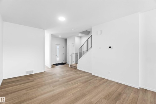 Open-concept living area featuring wood-finish flooring, white walls, and recessed lighting - 223 157 Avenue Ne, Edmonton, AB - Indoor Photo Showing Other Room