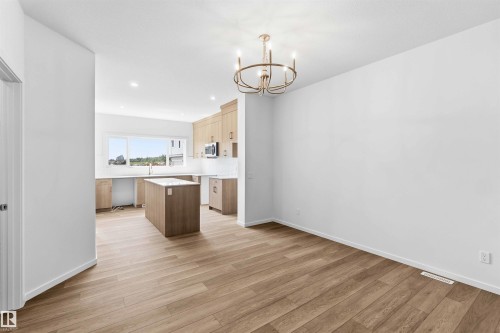 Open-concept living space featuring wood-finish flooring, a modern brass chandelier, and recessed lighting - 223 157 Avenue Ne, Edmonton, AB - Indoor Photo Showing Kitchen