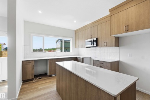 Modern kitchen featuring wood-finish cabinetry, white countertops, and a white subway tile backsplash - 223 157 Avenue Ne, Edmonton, AB - Indoor Photo Showing Kitchen