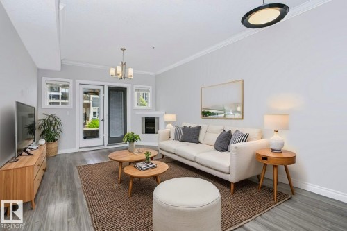 Bright living area featuring wood-finish flooring, a built-in fireplace, and crown molding - #137 10121 80 Av Nw, Edmonton, AB - Indoor Photo Showing Living Room