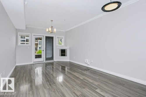Spacious room featuring wood-finish flooring, light grey wall paint, and white trim - #137 10121 80 Av Nw, Edmonton, AB - Indoor Photo Showing Other Room