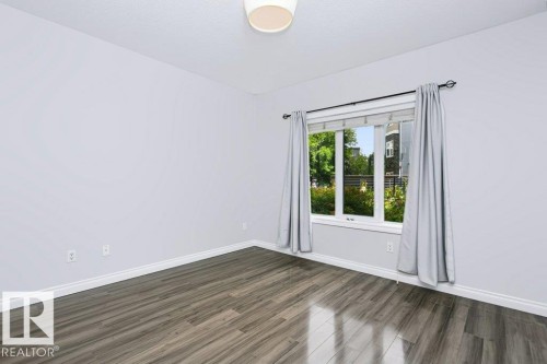 Recessed bay window with white trim, wood-finish flooring, light gray wall paint, white baseboards, and a semi-flush mount ceiling light - #137 10121 80 Av Nw, Edmonton, AB - Indoor Photo Showing Other Room