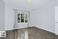 Spacious interior featuring wood-finish flooring, light grey walls, white trim, and a contemporary ceiling light fixture - 