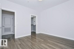 Spacious interior featuring wood-finish flooring, light gray walls, white trim, and a walk-in closet with built-in shelving - 