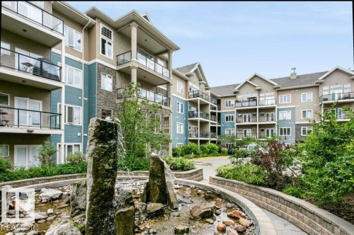 Multi-story residential building featuring balconies with glass railings, varied exterior siding, and stone accents - #137 10121 80 Av Nw, Edmonton, AB - Outdoor With Facade