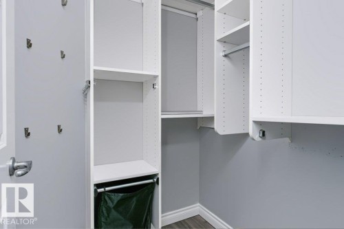 Custom closet system featuring white shelving units, adjustable shelves, integrated hanging rods, and multiple wall hooks - #137 10121 80 Av Nw, Edmonton, AB - Indoor