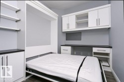 Murphy bed system featuring built-in cabinetry, floating shelves, integrated desk, and dark countertops - 