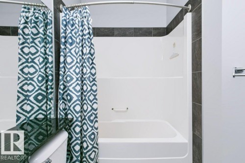 White tub/shower combination with integrated grab bar - #137 10121 80 Av Nw, Edmonton, AB - Indoor Photo Showing Other Room
