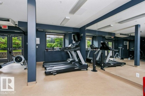 Fitness area featuring a patterned floor, floor-to-ceiling mirrors, recessed lighting, and wall-mounted windows - #137 10121 80 Av Nw, Edmonton, AB - Indoor Photo Showing Gym Room