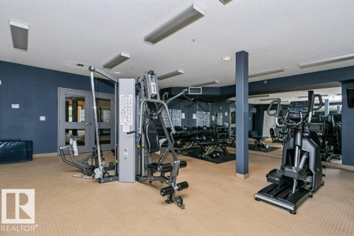 Fitness center featuring carpet flooring, blue accent walls, integrated lighting, and mirrored walls - #137 10121 80 Av Nw, Edmonton, AB - Indoor Photo Showing Gym Room