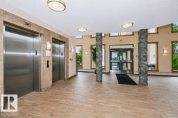 Entry foyer featuring tile flooring, stone-clad columns, and dual stainless steel elevators - 