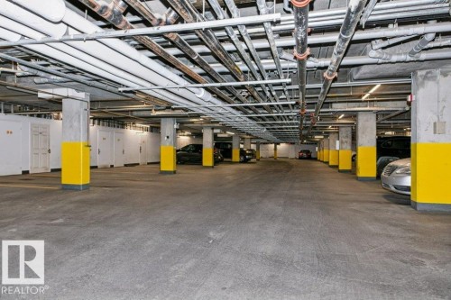 Underground parking garage featuring concrete pillars, exposed ceiling conduits, and individual storage units - #137 10121 80 Av Nw, Edmonton, AB - Indoor Photo Showing Garage