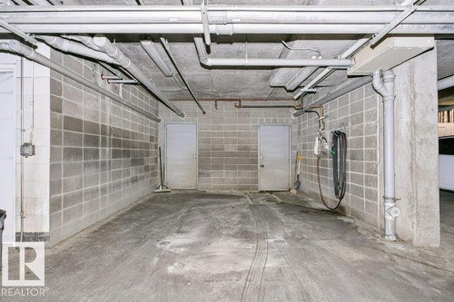 Concrete block walls and ceiling-mounted utilities define this functional space - #137 10121 80 Av Nw, Edmonton, AB - Indoor Photo Showing Garage