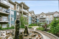 Multi-story residential building featuring balconies with glass railings, varied exterior siding, and stone accents - 