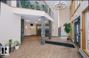 Spacious lobby featuring wood-finish flooring, stacked stone columns, a multi-story ceiling, and a prominent chandelier - #137 10121 80 Av Nw, Edmonton, AB  - Indoor Photo Showing Other Room 