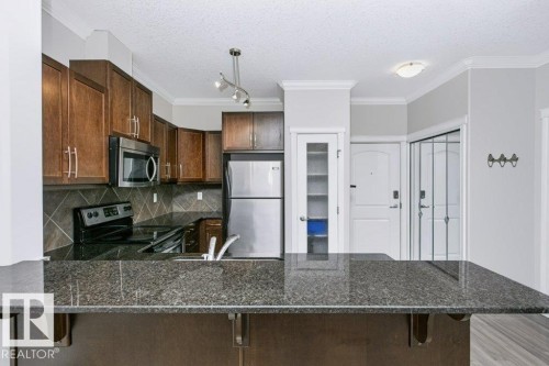 Kitchen featuring a large breakfast bar with granite-style countertop - #137 10121 80 Av Nw, Edmonton, AB - Indoor Photo Showing Kitchen