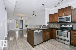 Kitchen featuring wood cabinetry, stainless steel appliances, dark countertops, and a tiled backsplash - 