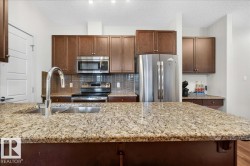 Kitchen island with stone-finish countertop and undermount stainless steel sink featuring a gooseneck faucet - 
