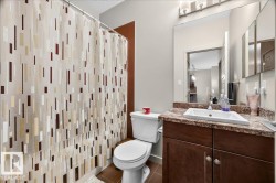 Bathroom featuring a brown wood-finish vanity with a light-colored countertop, an undermount sink, and a wall-mounted mirror - 