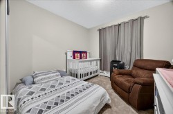 Carpeted room with a textured ceiling, neutral-toned walls, and a window featuring dark grey drapery - 