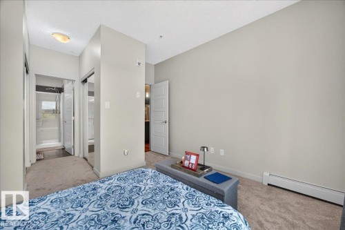 Carpeted bedroom featuring light gray walls and a ceiling light fixture - 106 320 Ambleside Link Sw, Edmonton, AB - Indoor Photo Showing Bedroom
