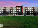 Contemporary building exterior featuring a multi-tone facade with dark grey, light grey, and orange accents - 106 320 Ambleside Link Sw, Edmonton, AB  - Outdoor With Balcony 