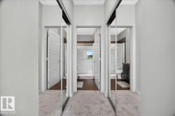 Mirrored sliding closet doors reflecting a modern bathroom with a glass-enclosed shower, dark wood-finish vanity, and wood-finish flooring - 