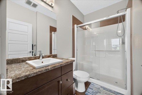 Bathroom with a dark wood-finish vanity, a rectangular undermount sink, and a speckled countertop - 106 320 Ambleside Link Sw, Edmonton, AB - Indoor Photo Showing Bathroom