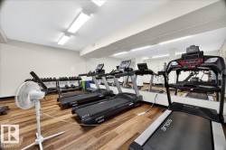 Dedicated fitness area featuring multiple treadmills, wood-finish flooring, a full-wall mirror, and overhead fluorescent lighting - 
